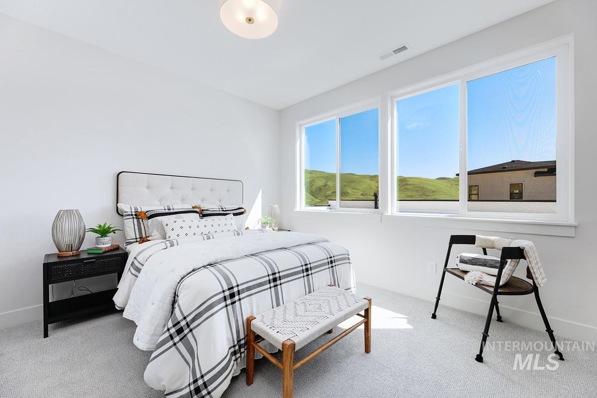 Plush carpeting and bright white walls define this space, featuring a built-in upholstered headboard