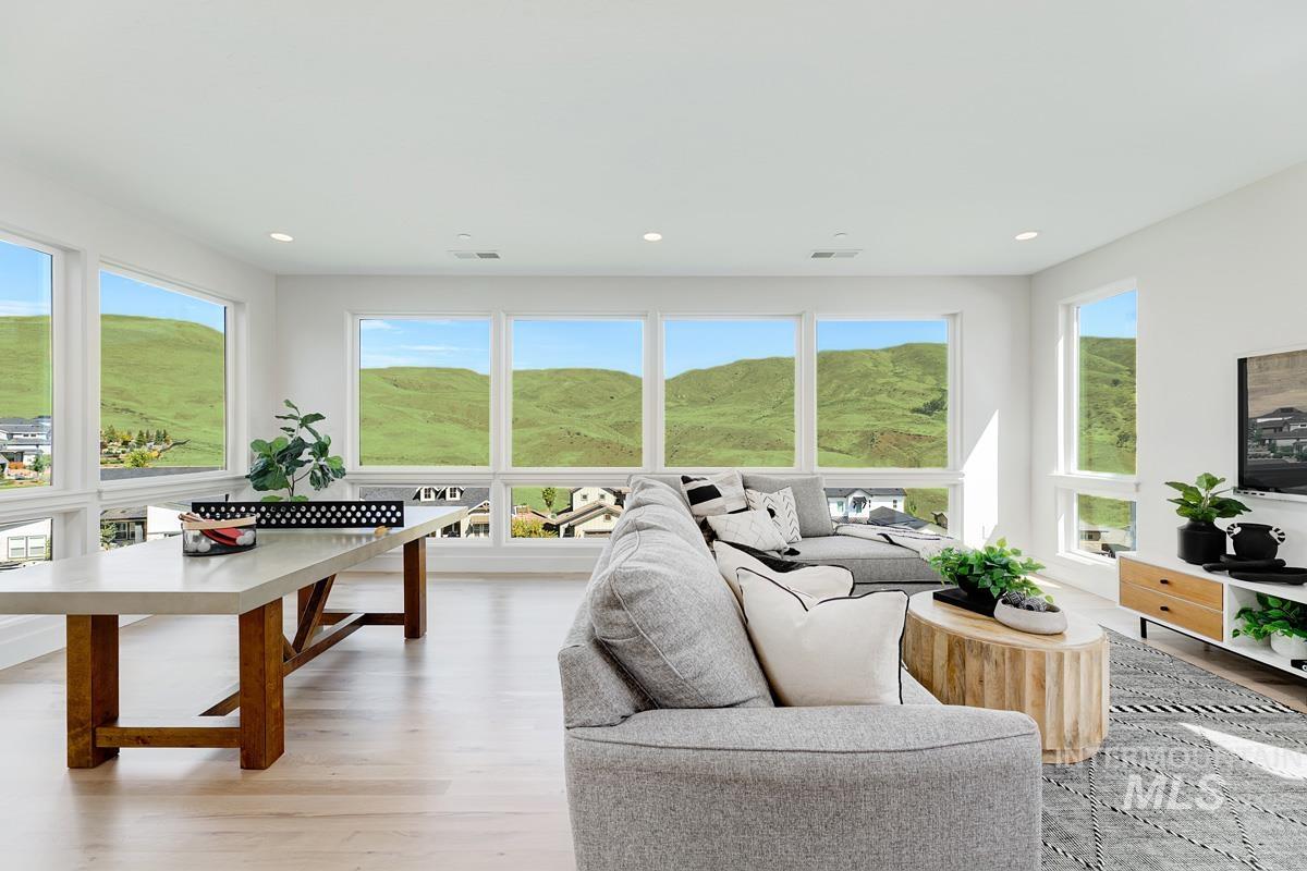 Bright living space featuring multiple large windows, recessed lighting, light wood-finish flooring, and white walls