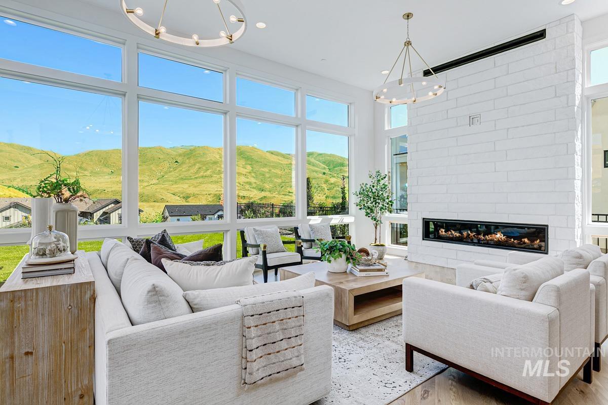 Bright living space featuring expansive windows, a linear gas fireplace set into a white brick wall, and wood-finish flooring