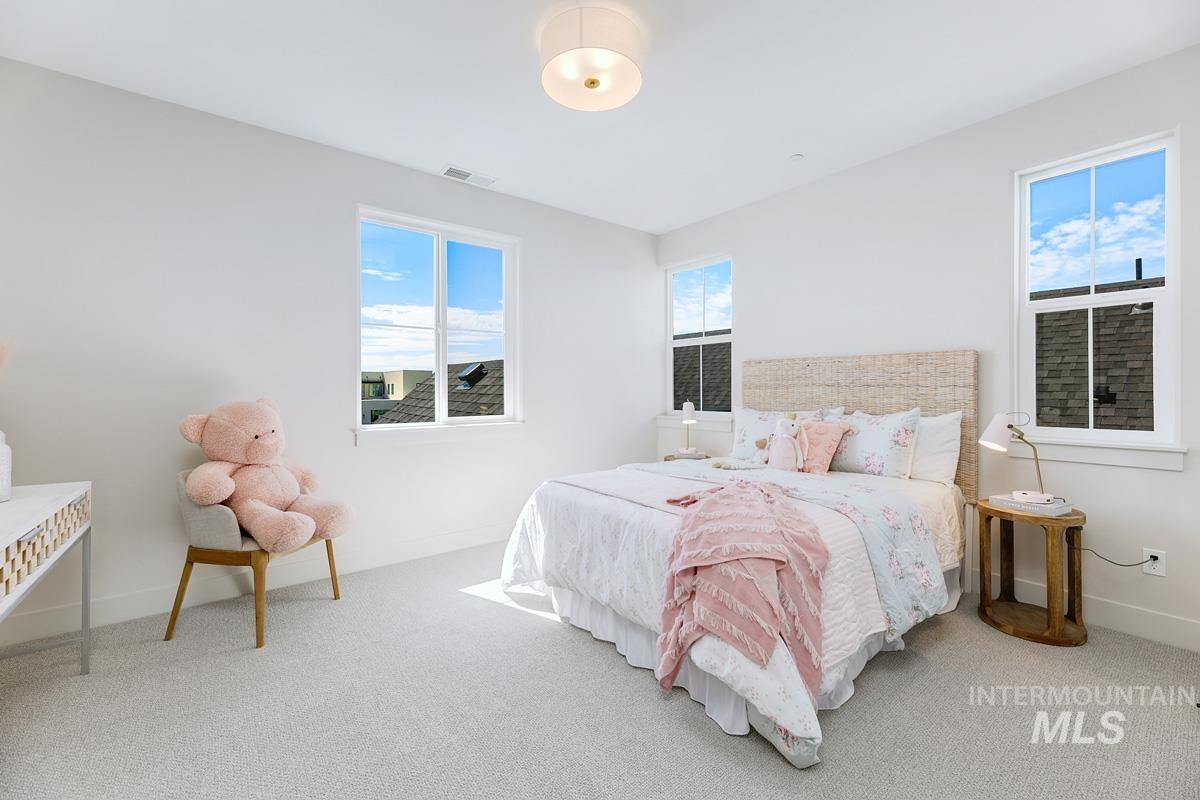 Bedroom featuring light grey carpeting and multiple windows with white trim