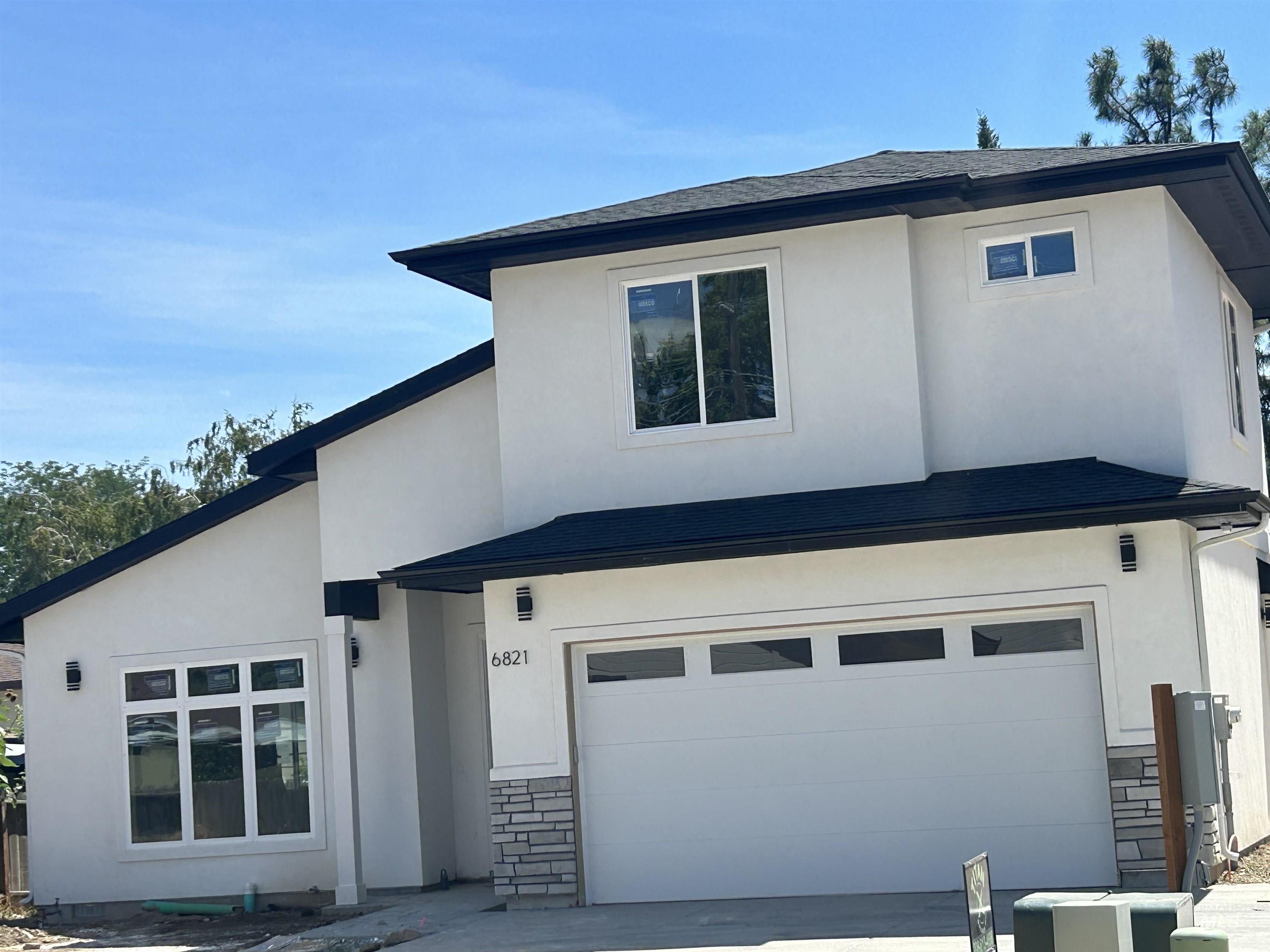 View of front facade featuring stone siding, a garage, and stucco siding