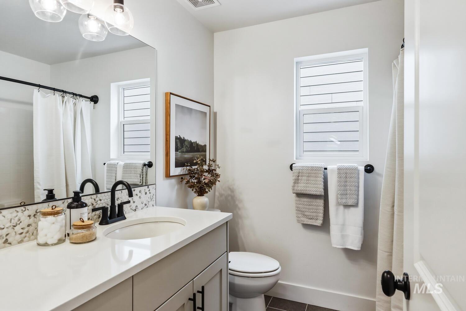 Bathroom with vanity, curtained shower, and dark tile patterned floors