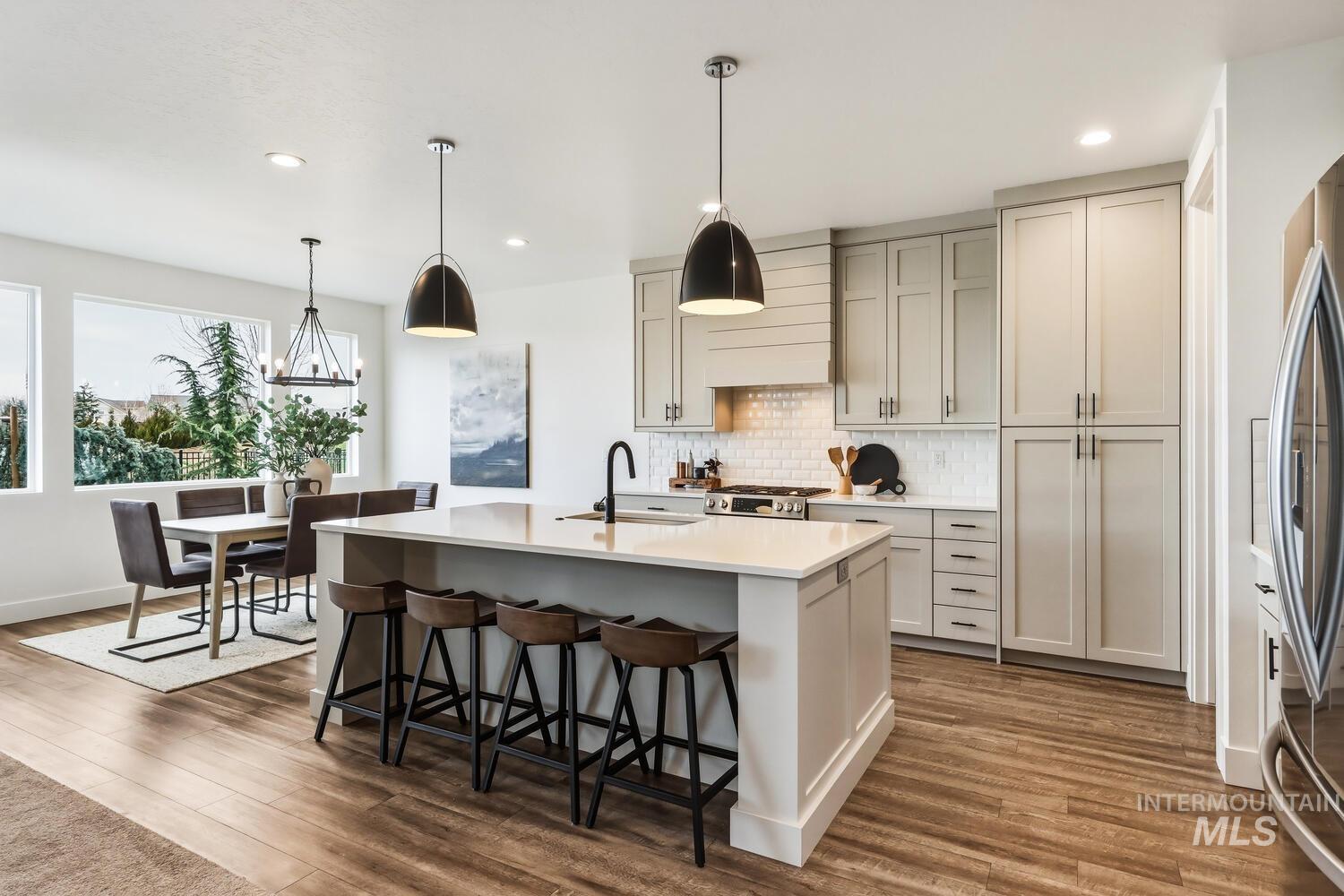 Kitchen with pendant lighting, a kitchen breakfast bar, decorative backsplash, an island with sink, and stainless steel appliances