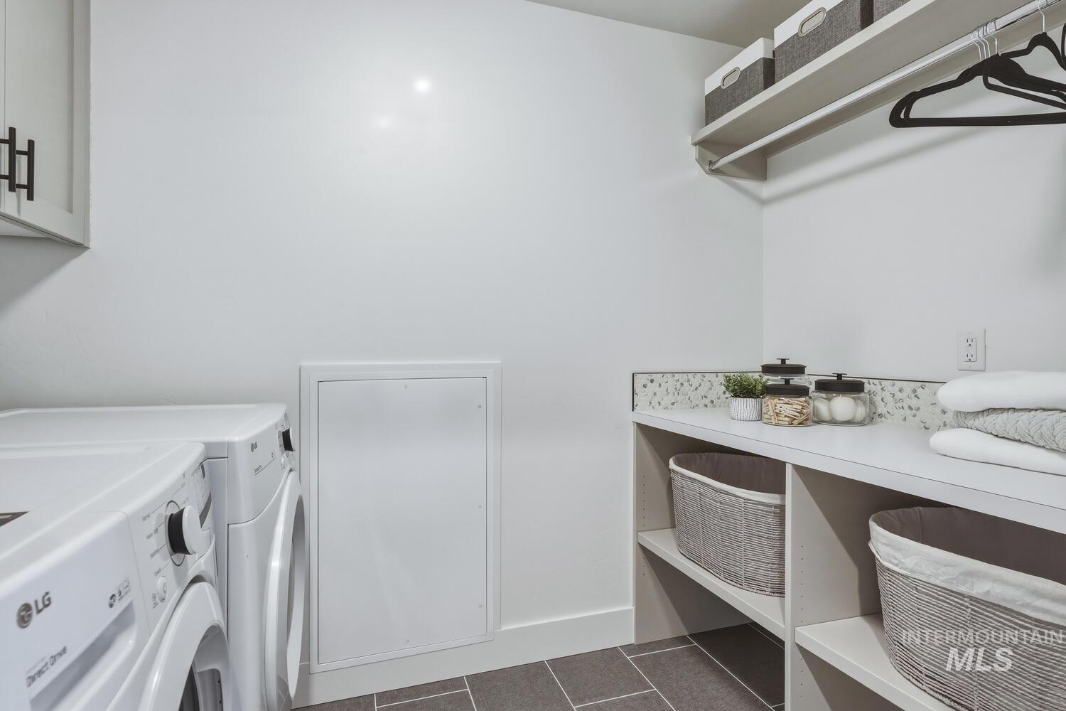 Laundry area with dark tile patterned floors and washing machine and clothes dryer