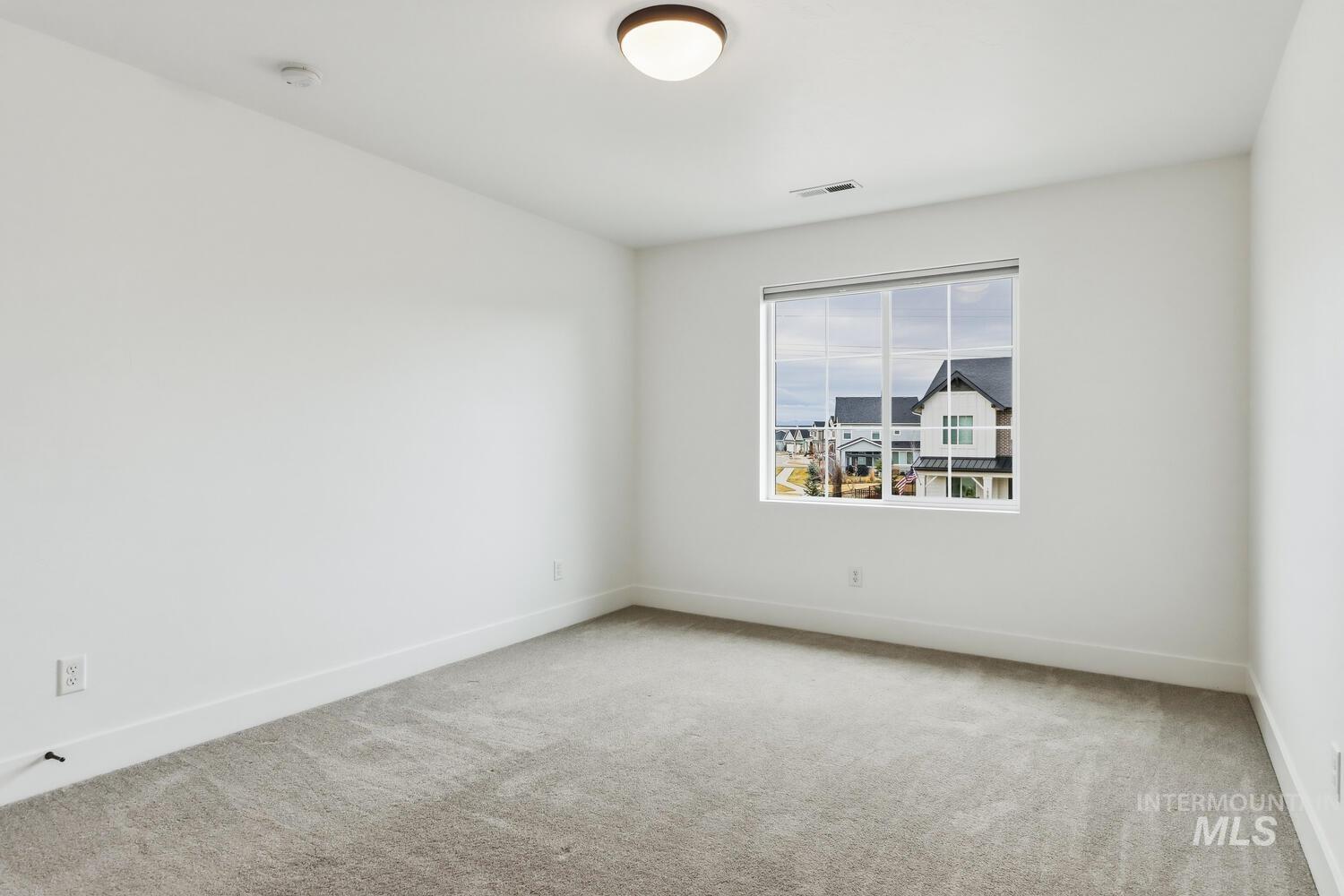 Empty room with light colored carpet and baseboards