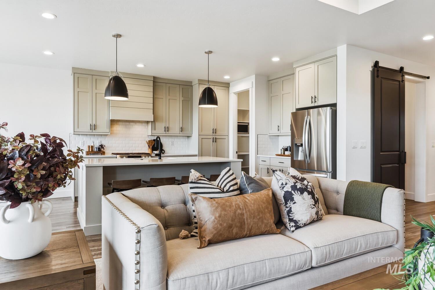 Living room with a barn door, light wood finished floors, and recessed lighting