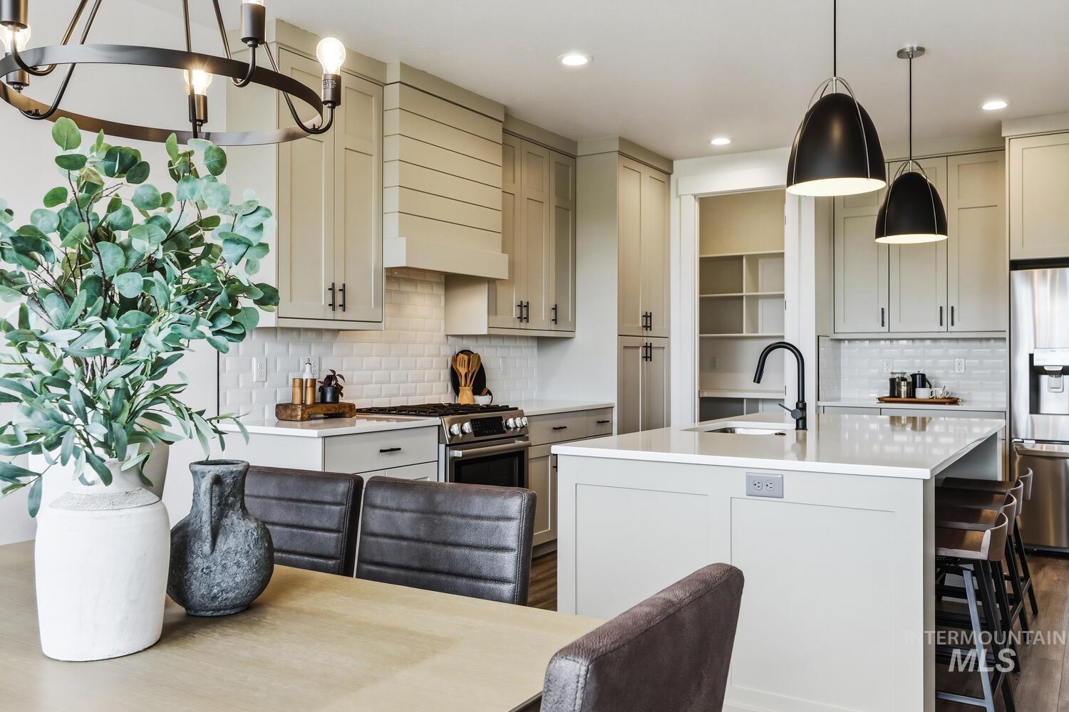 Kitchen with decorative light fixtures, stainless steel appliances, light stone counters, cream cabinets, and dark wood finished floors