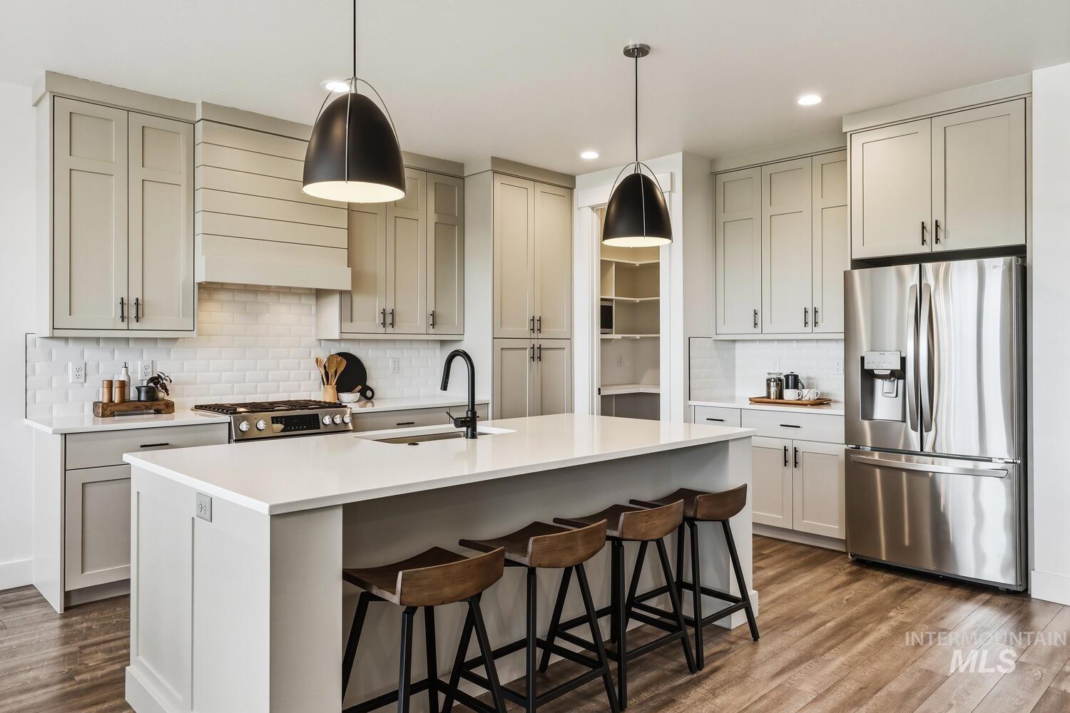 Kitchen featuring stainless steel appliances, pendant lighting, dark wood-style floors, a breakfast bar area, and tasteful backsplash