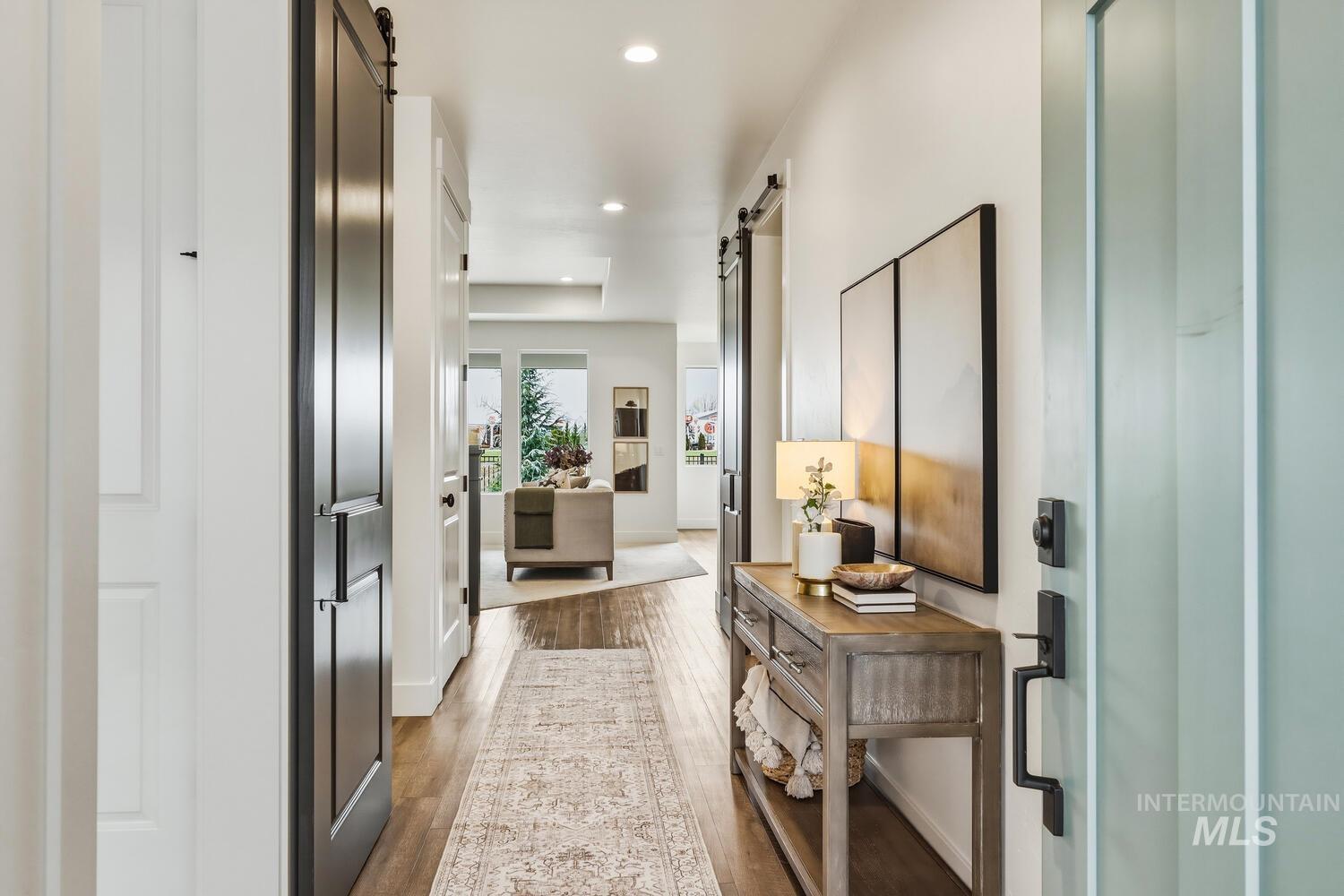 Hallway with a barn door, recessed lighting, and wood finished floors