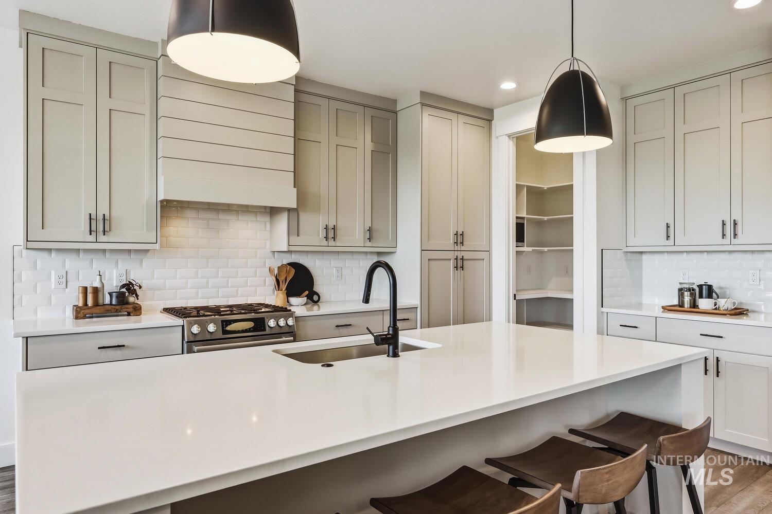 Kitchen featuring backsplash, stainless steel gas stove, dark wood-style floors, and pendant lighting