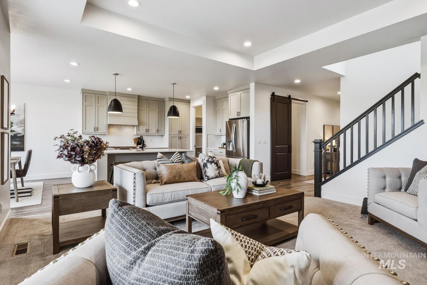 Living room with a barn door, wood finished floors, recessed lighting, and a raised ceiling
