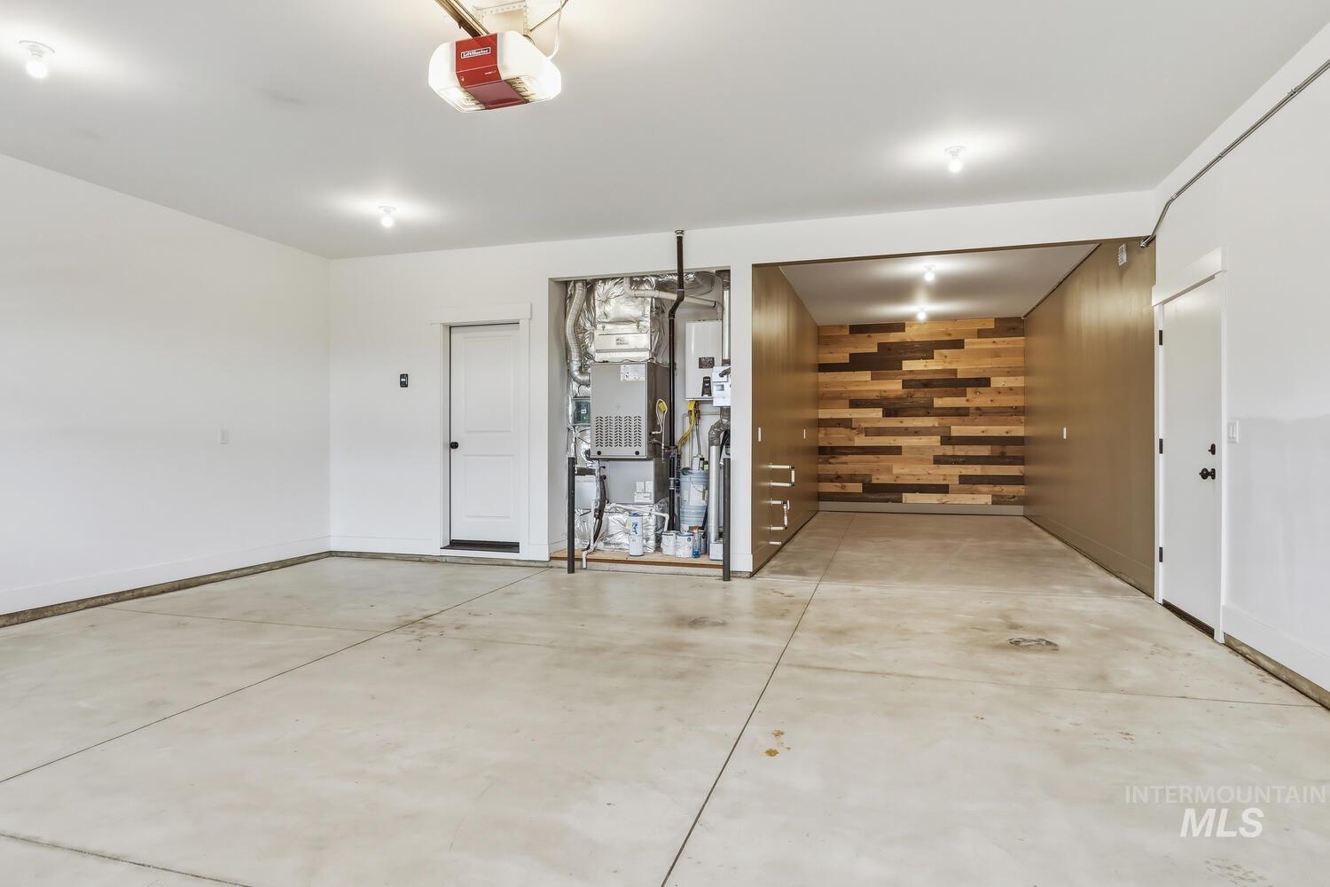 Garage featuring heating unit, wooden walls, tankless water heater, and a garage door opener