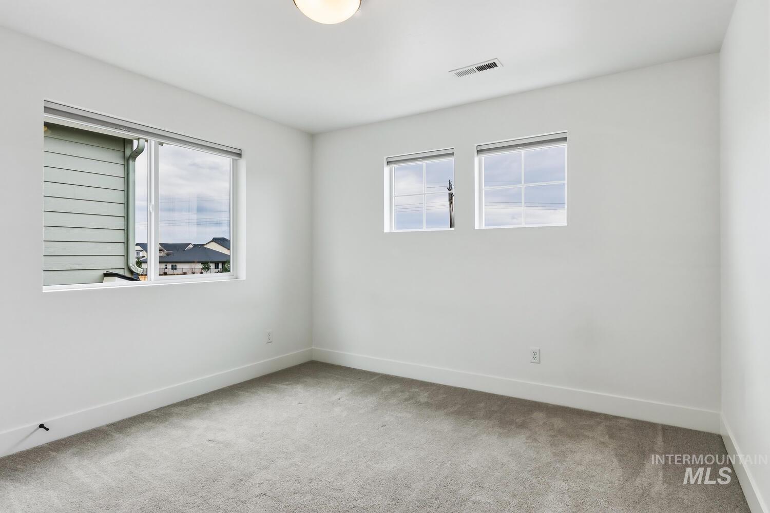 Empty room with light colored carpet and plenty of natural light
