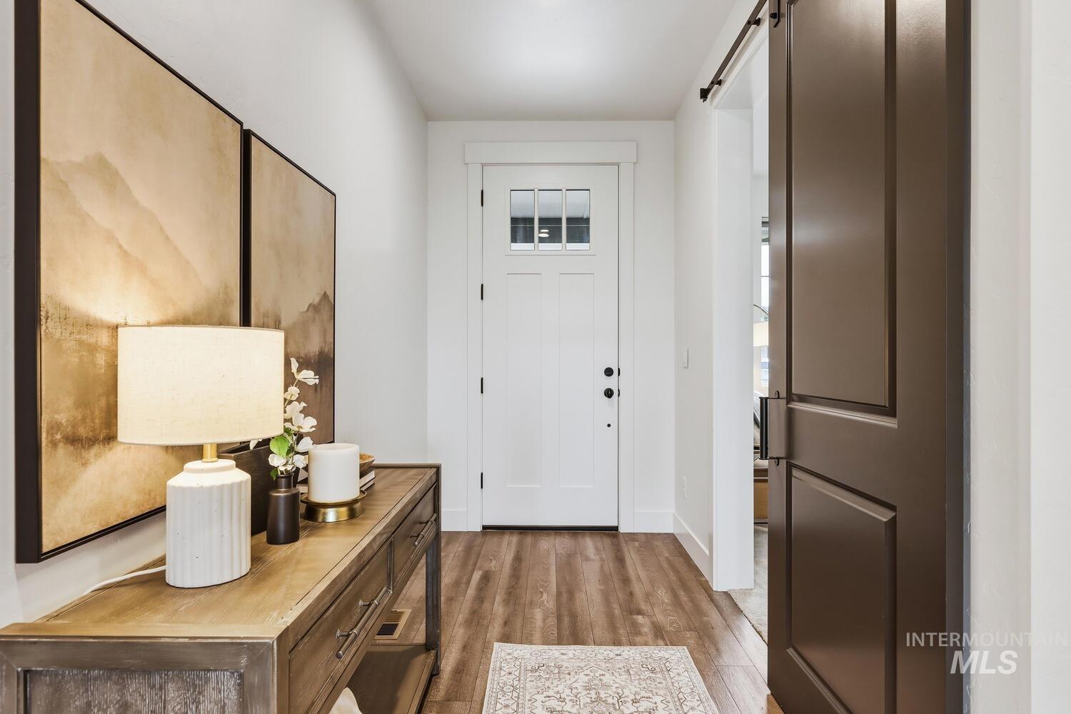 Foyer with light wood-style floors and a barn door