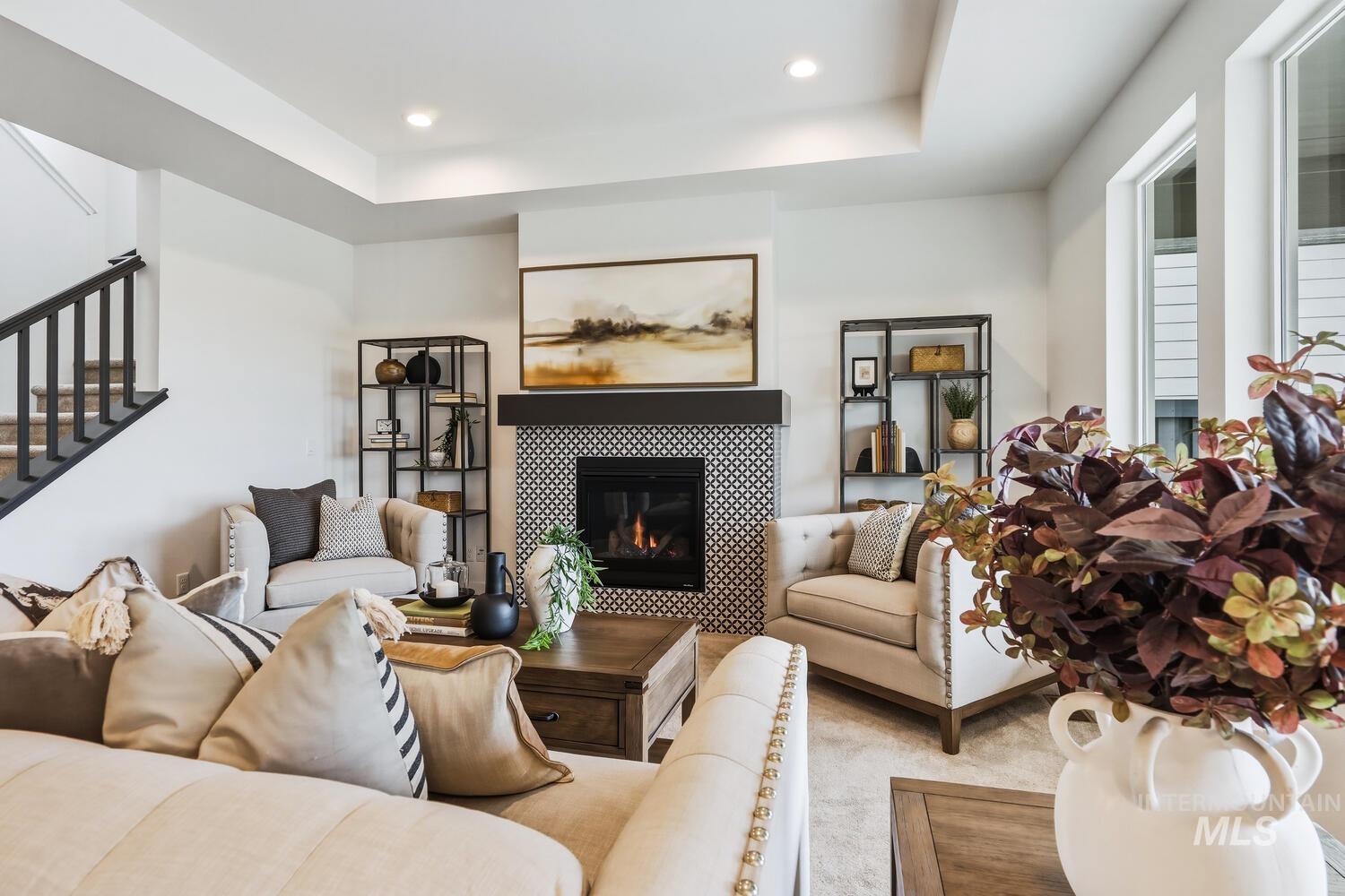 Carpeted living area with a tiled fireplace, a tray ceiling, and recessed lighting