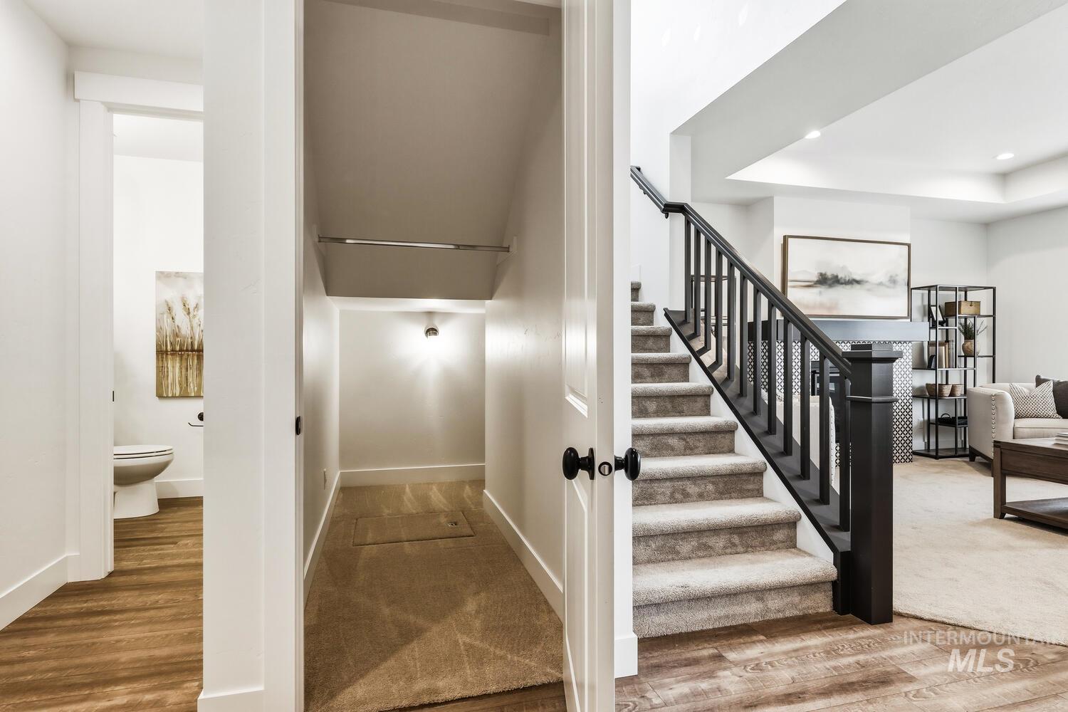 Staircase featuring wood finished floors, recessed lighting, a raised ceiling, and carpet