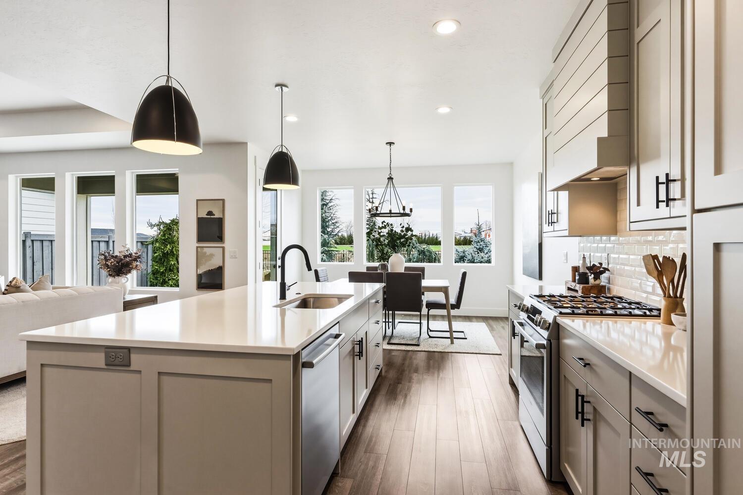 Kitchen featuring stainless steel appliances, dark wood-type flooring, an island with sink, light stone countertops, and open floor plan