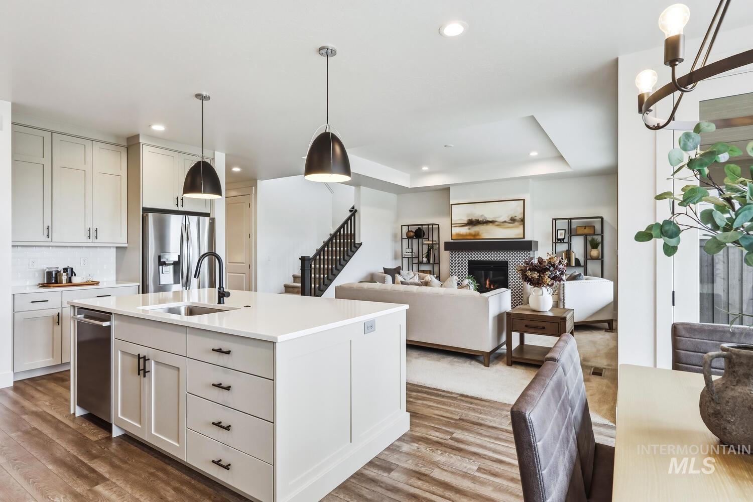 Kitchen featuring hanging light fixtures, light wood-style floors, open floor plan, a tiled fireplace, and a center island with sink