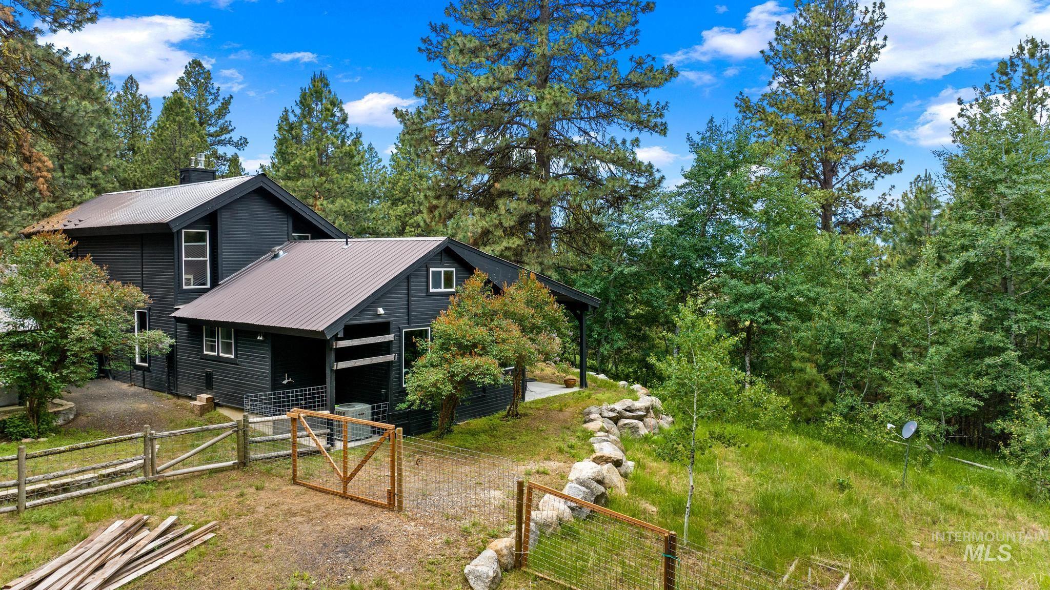 Rear view of house featuring a gate, a metal roof, and a chimney