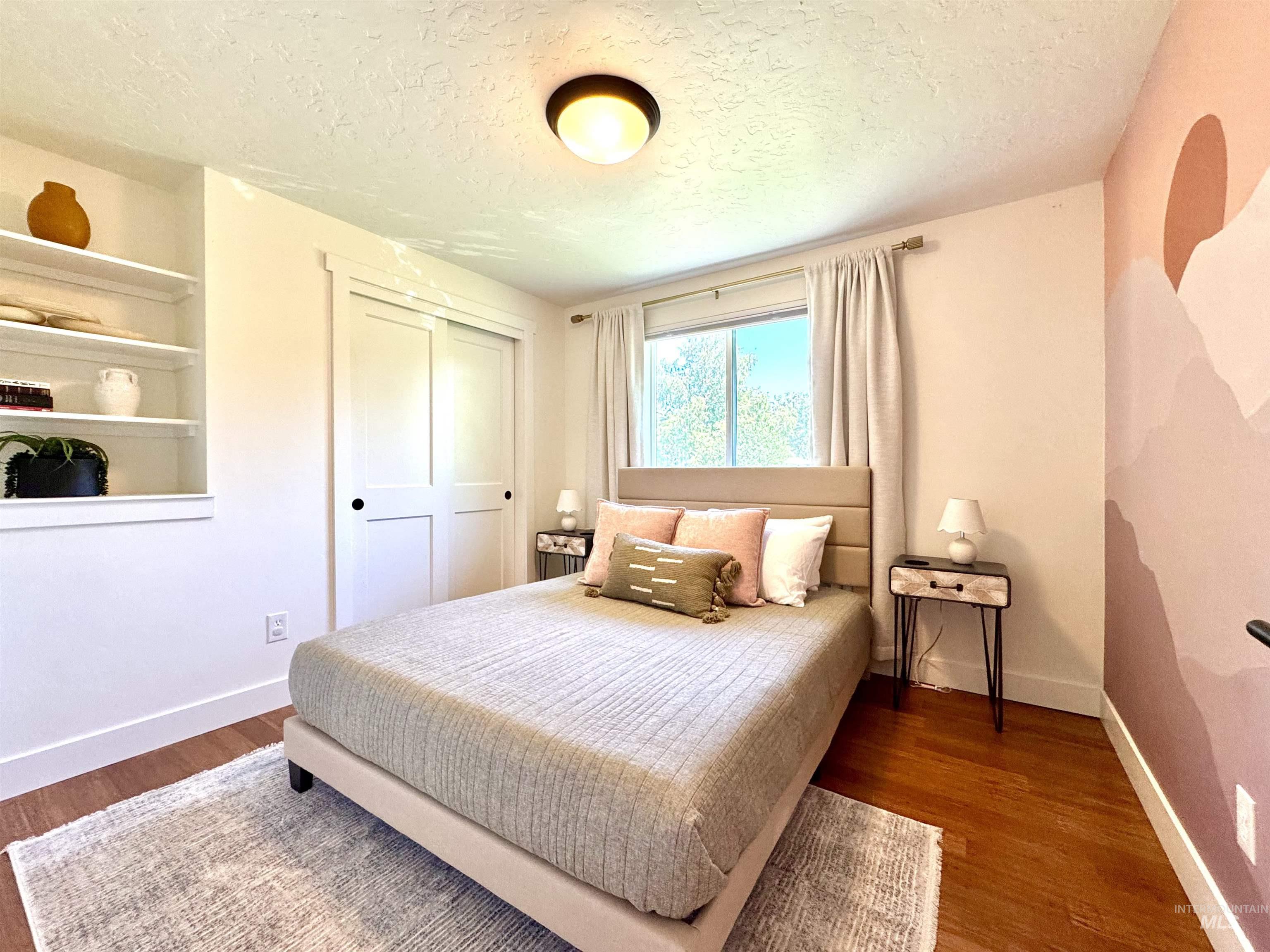 Bedroom with a textured ceiling, dark wood-style floors, and a closet