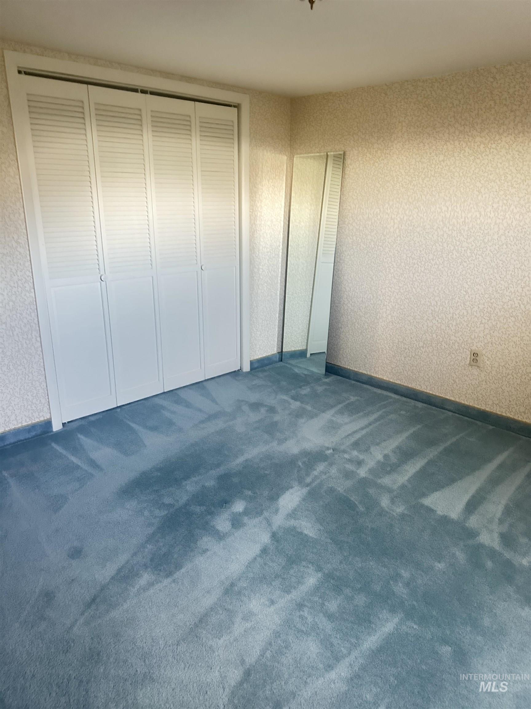Unfurnished bedroom with dark carpet and a closet