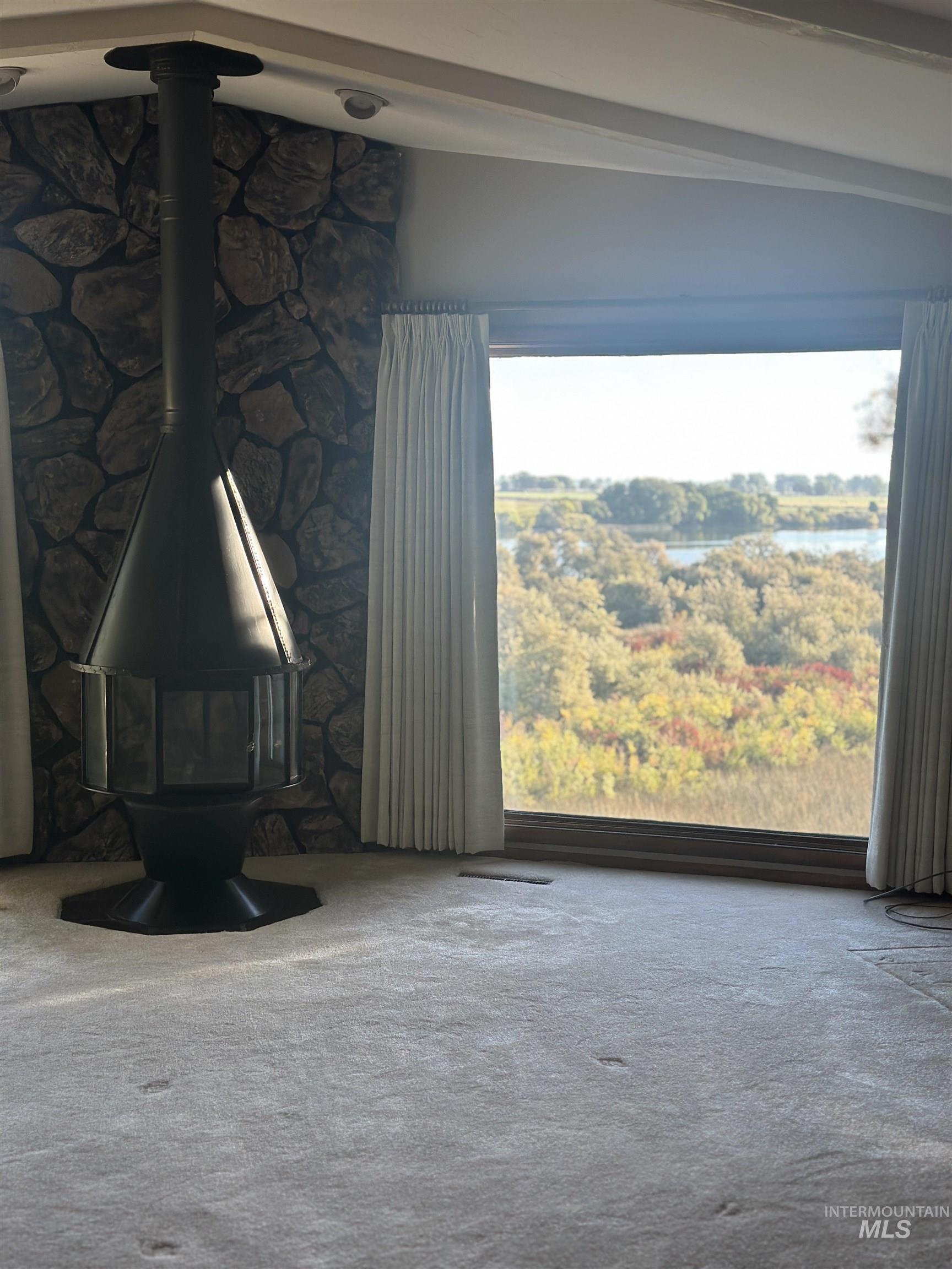 Unfurnished living room featuring a wood stove and carpet floors