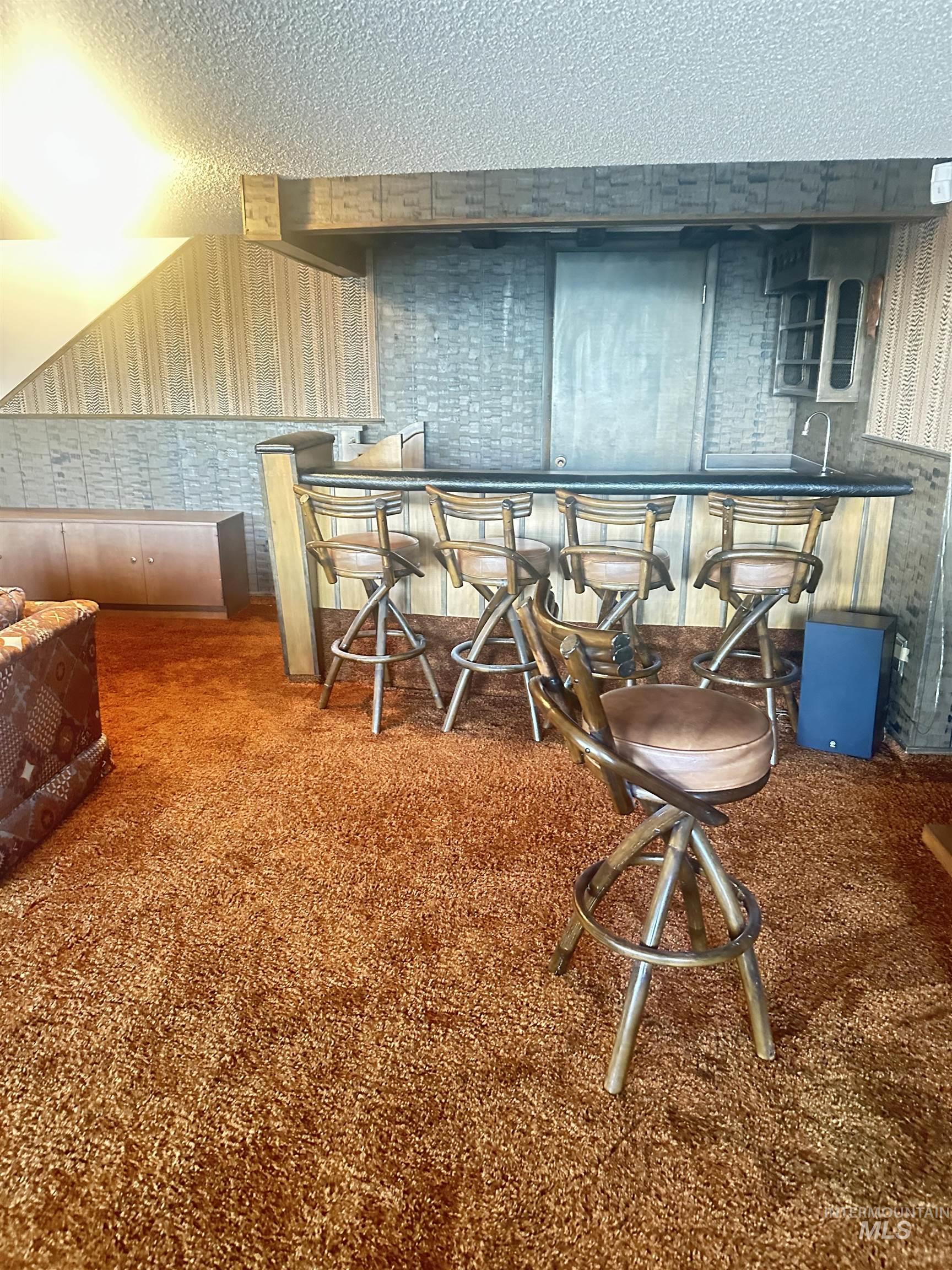 Office area with wallpapered walls, carpet floors, and a textured ceiling