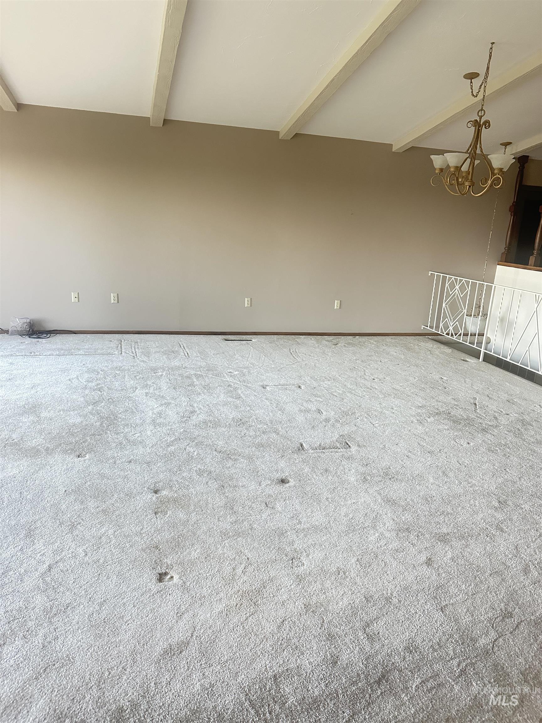 Carpeted spare room with beamed ceiling and a chandelier