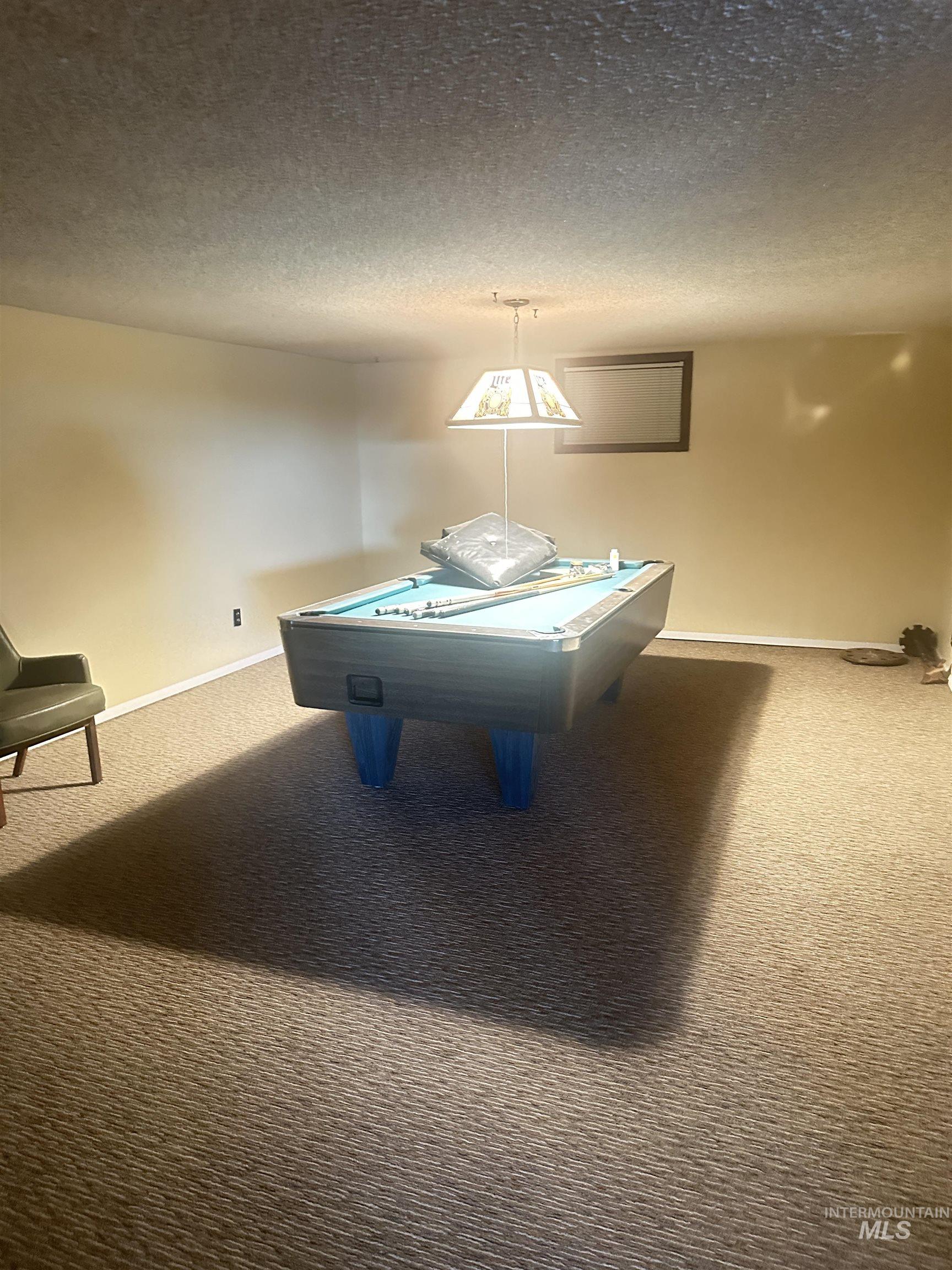 Game room with carpet floors, a textured ceiling, and billiards table