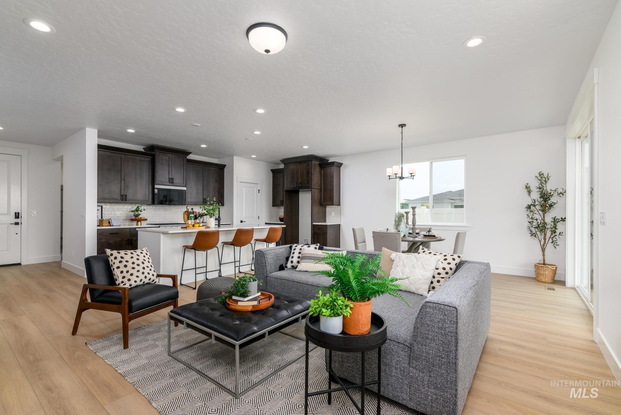 Living room with light wood-style floors and suspended lighting