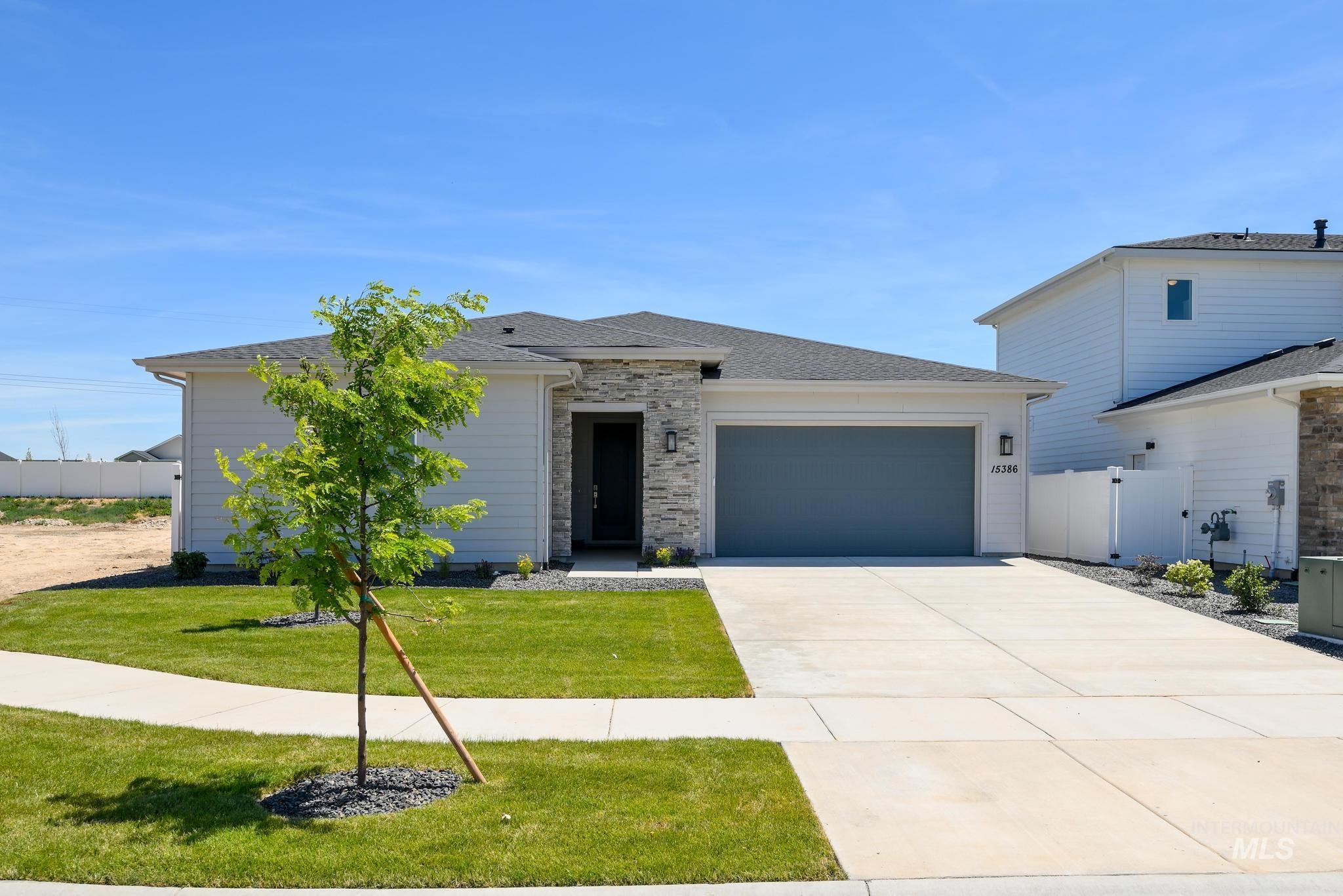 View of front of property featuring concrete driveway, a garage, a shingled roof, and a gate