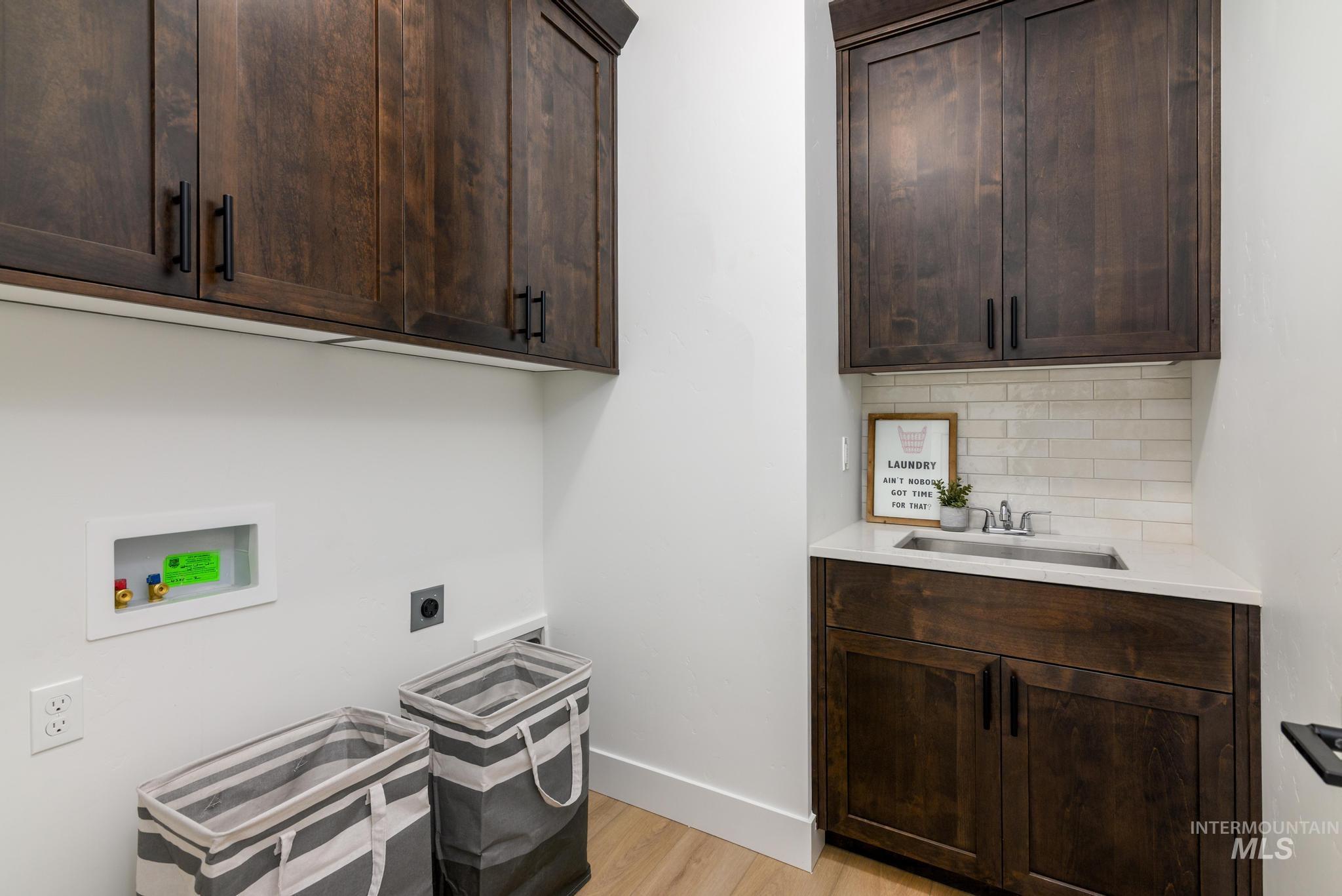Laundry room with cabinet space, hookup for a washing machine, light wood-style flooring, and hookup for an electric dryer