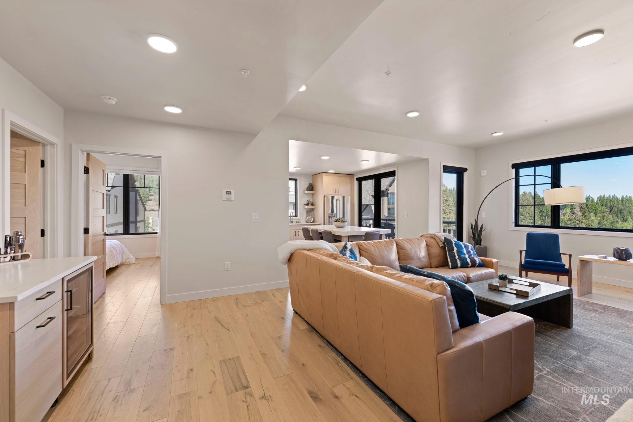 Living room featuring light wood-style floors, plenty of natural light, beverage cooler, and recessed lighting