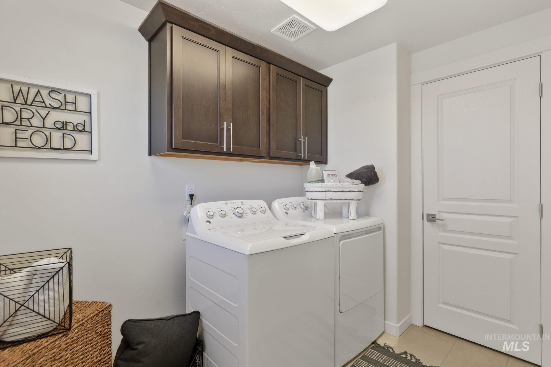 Washroom with cabinet space, washing machine and clothes dryer, and light tile patterned flooring