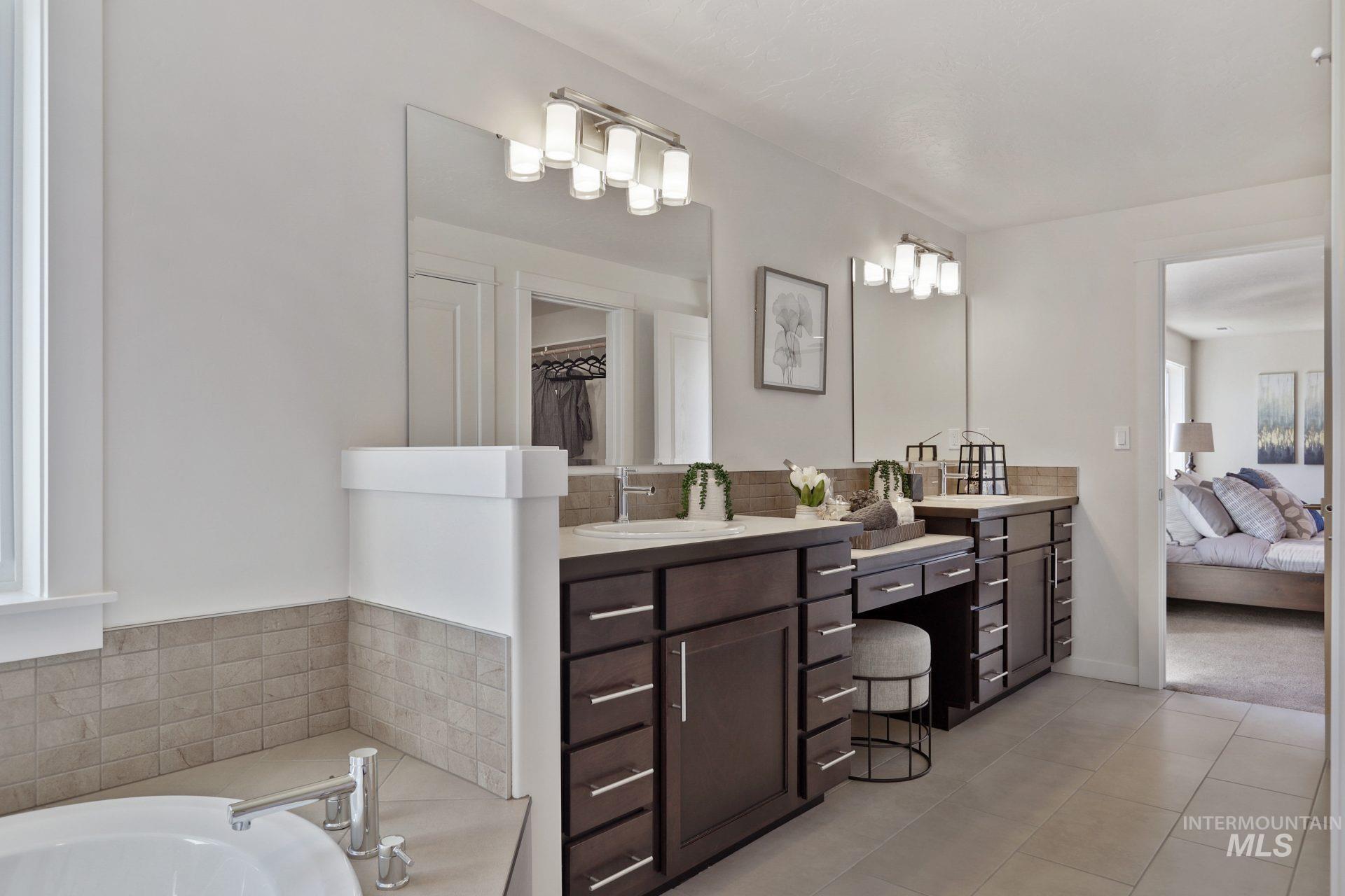 Full bathroom with connected bathroom, vanity, a spacious closet, a tub to relax in, and light tile patterned floors
