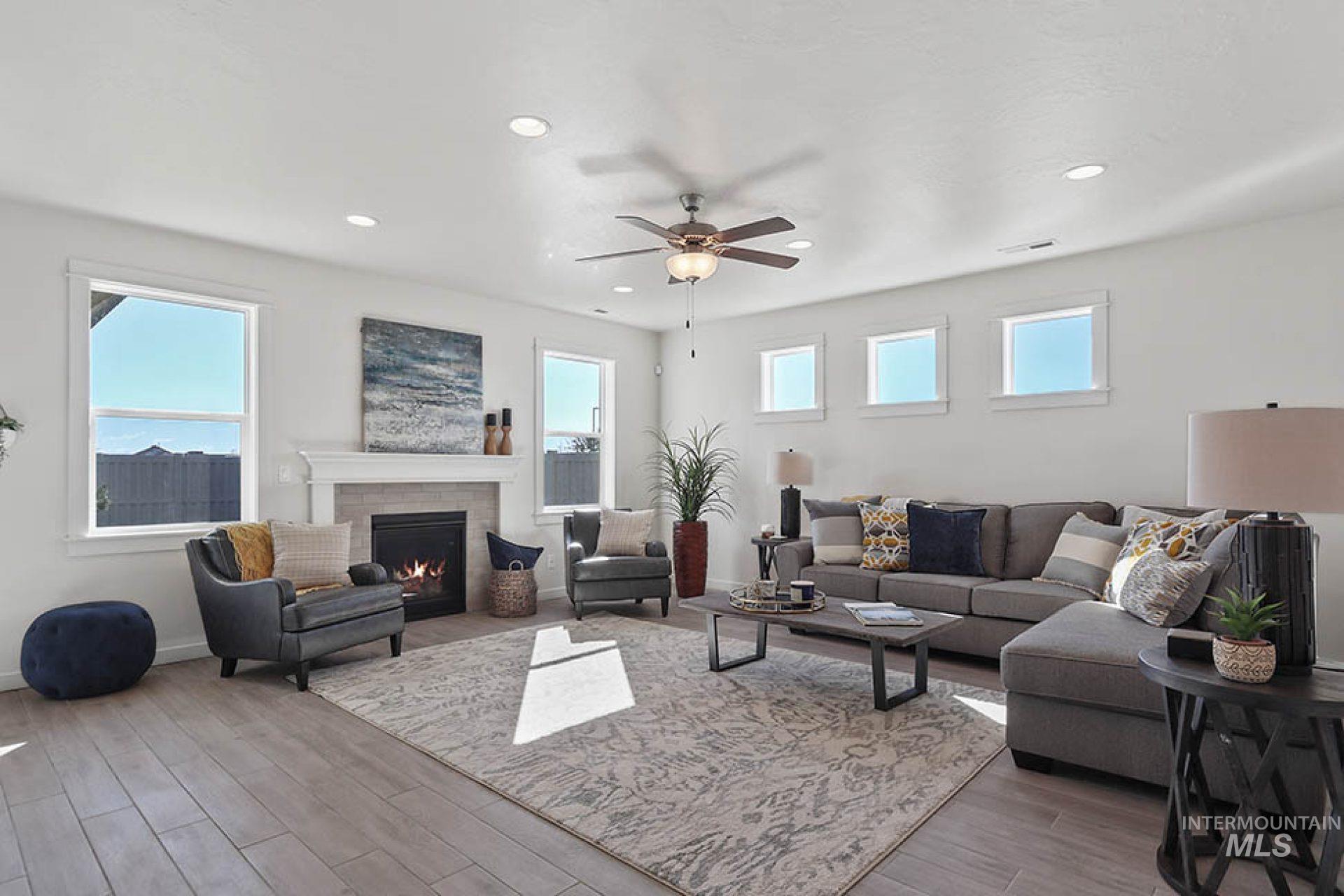 Living area featuring wood finished floors, a ceiling fan, a fireplace, recessed lighting, and healthy amount of natural light