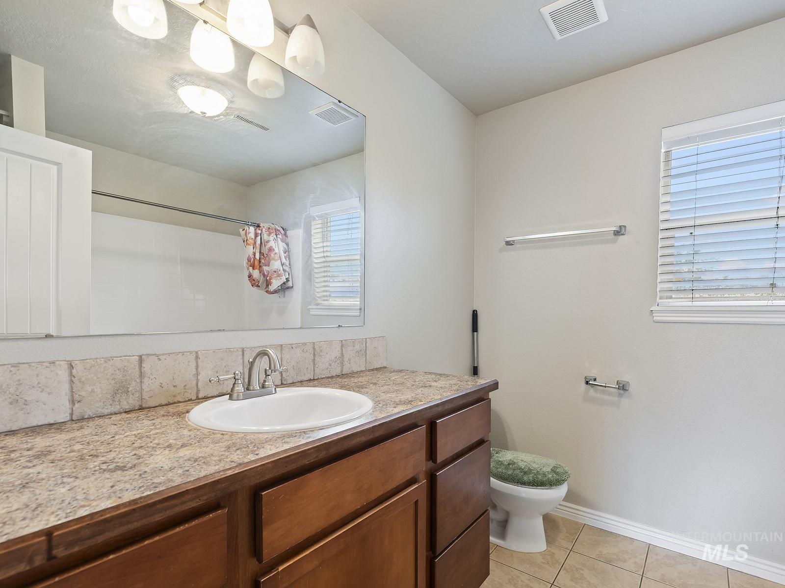 Full bath featuring vanity, light tile patterned floors, healthy amount of natural light, and curtained shower