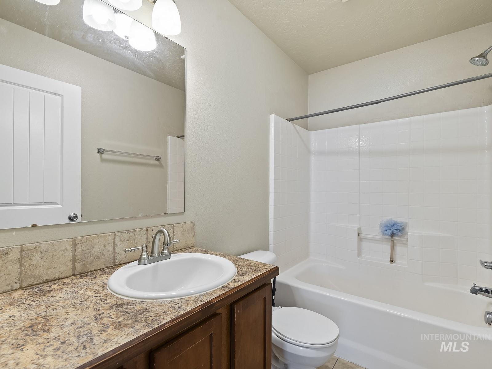 Full bath featuring bathtub / shower combination, vanity, and a textured ceiling