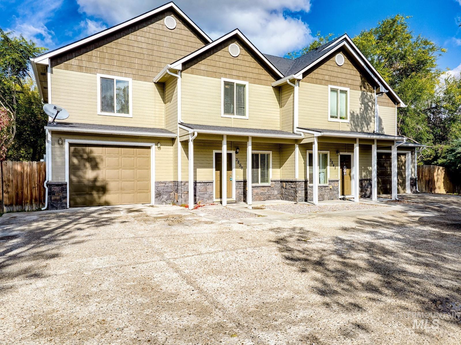 Craftsman-style house featuring stone siding, covered porch, an attached garage, and driveway