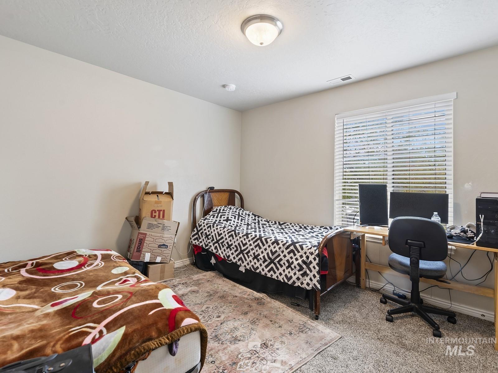 Bedroom with carpet floors, a textured ceiling, and a desk