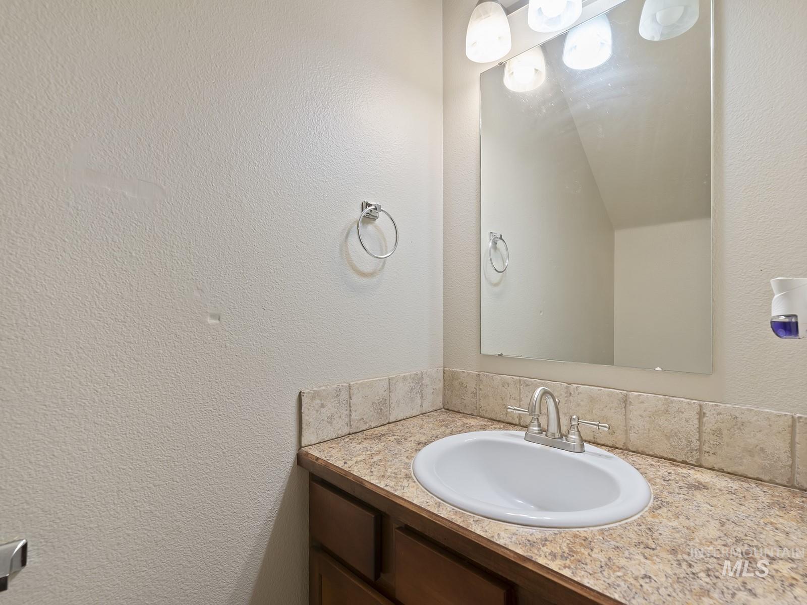 Bathroom featuring a textured wall and vanity