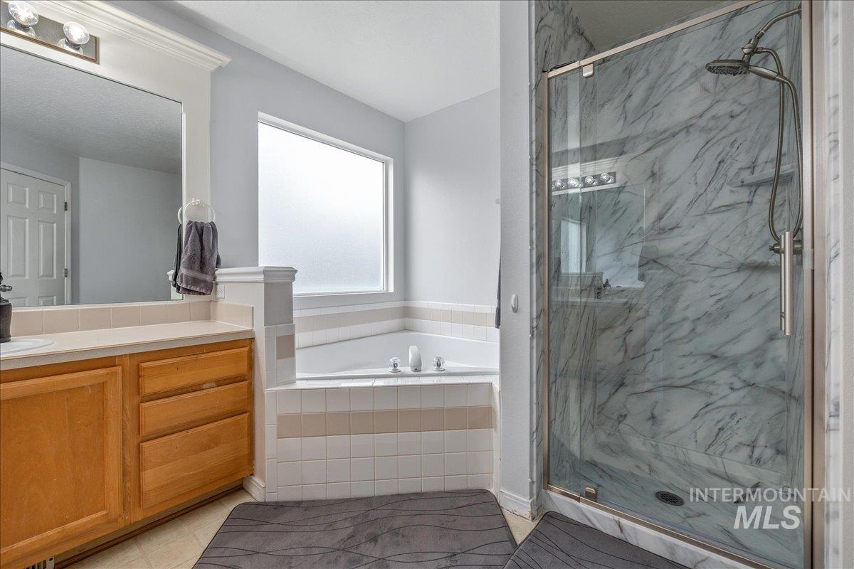 Bathroom featuring a marble finish shower, vanity, and a bath