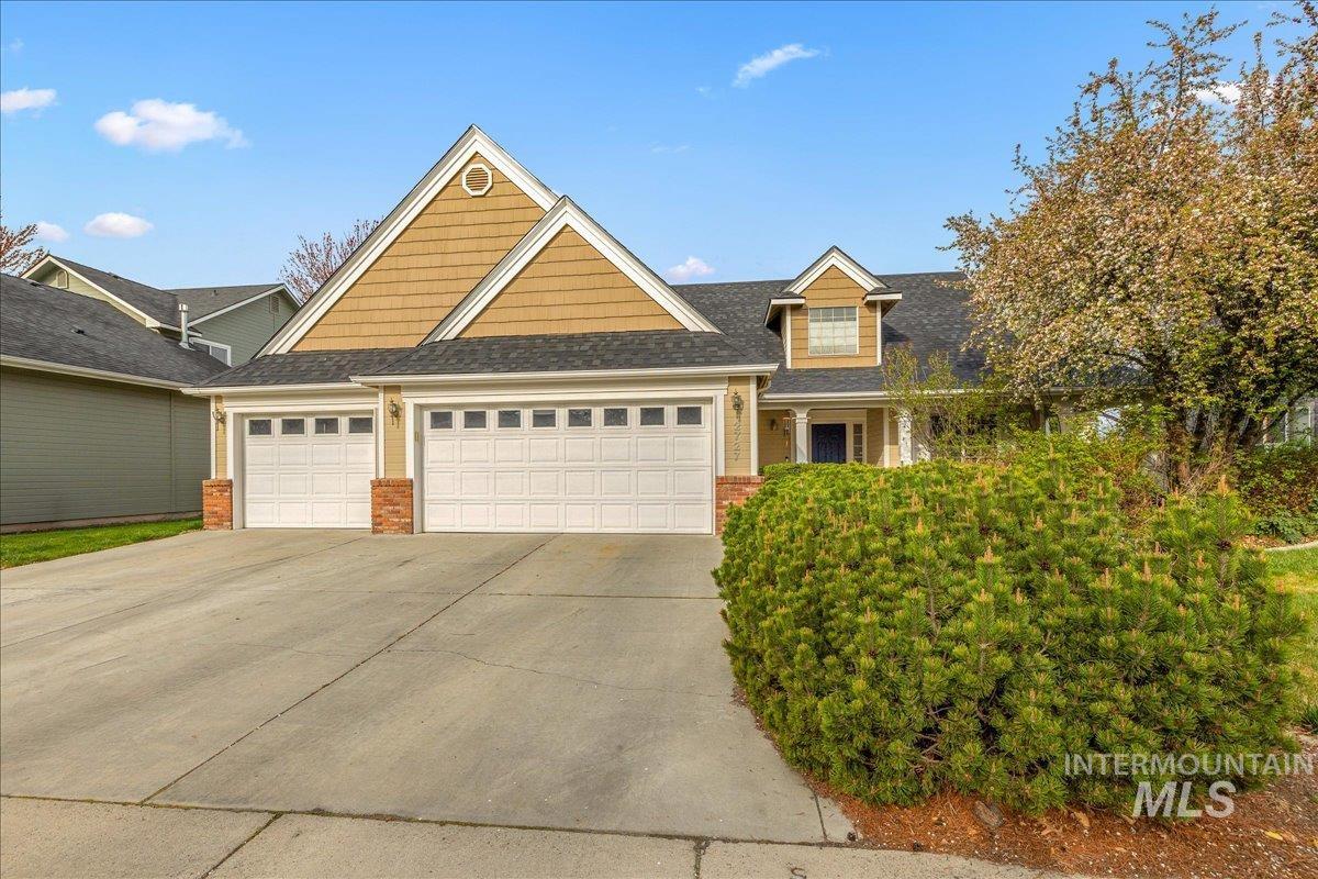 View of front of home with an attached garage, driveway, brick siding, and roof with shingles