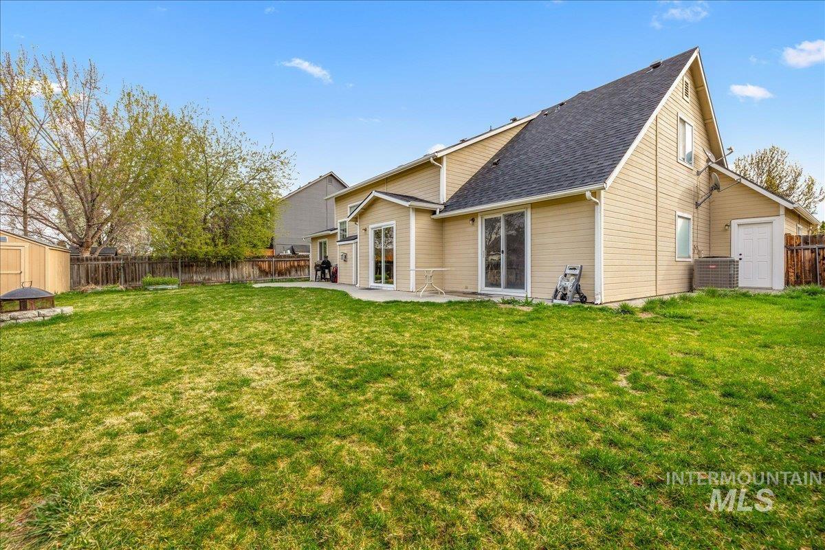 Rear view of property featuring a shed, a fenced backyard, roof with shingles, and a patio