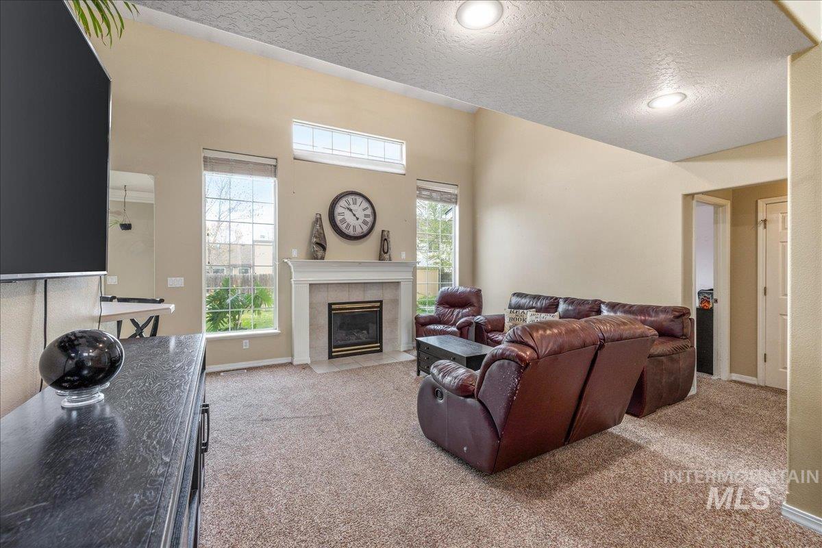 Living area featuring a textured ceiling, light carpet, and a tiled fireplace