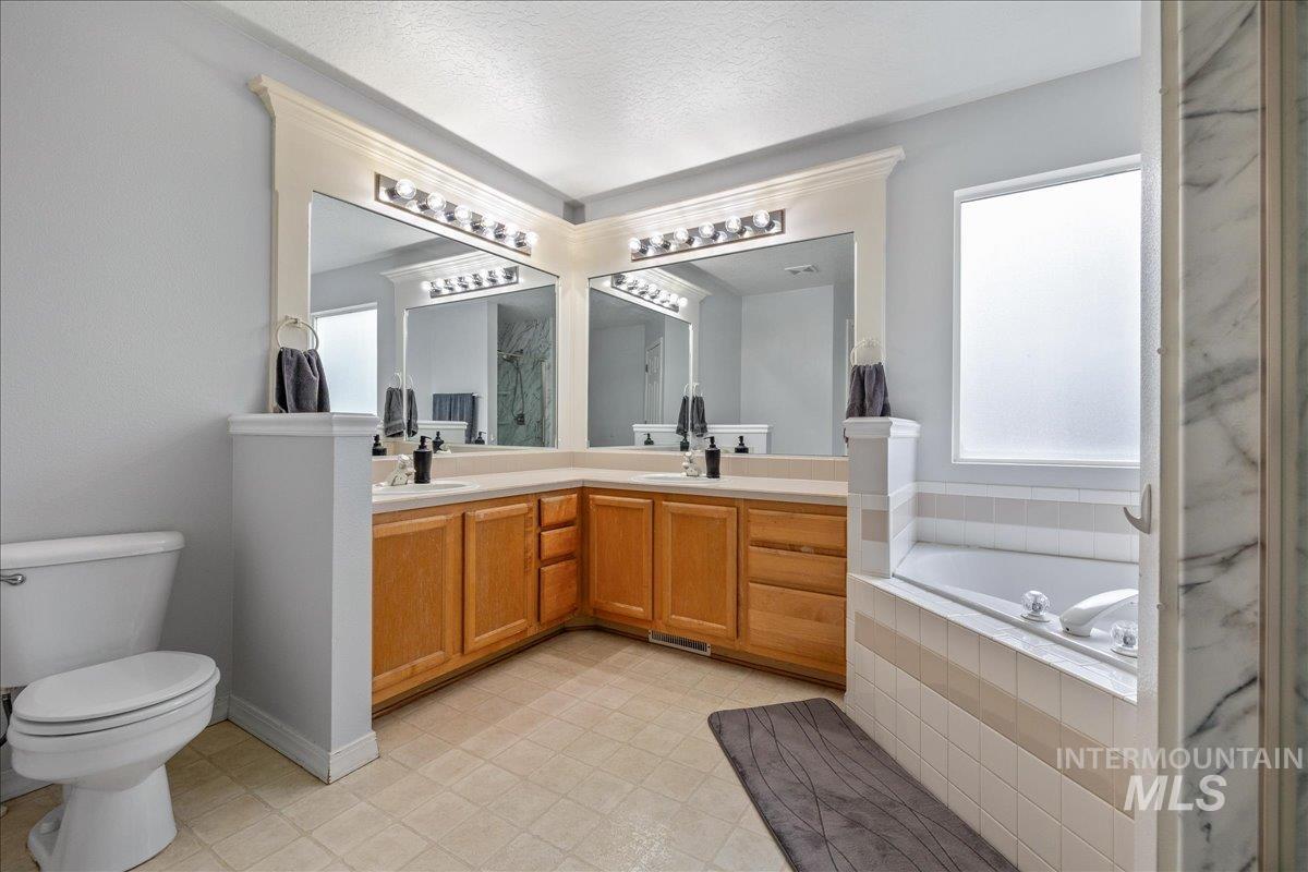 Full bathroom featuring double vanity, a bath, and walk in shower