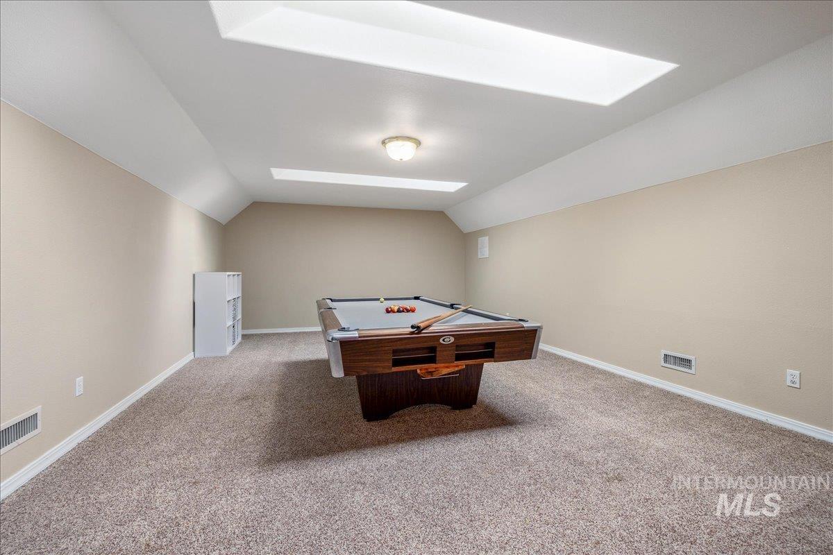 Game room with a skylight, light carpet, billiards table, and vaulted ceiling