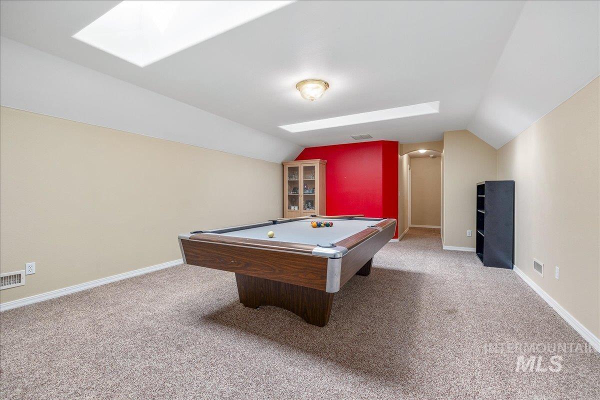 Rec room featuring light carpet, a skylight, billiards table, lofted ceiling, and arched walkways