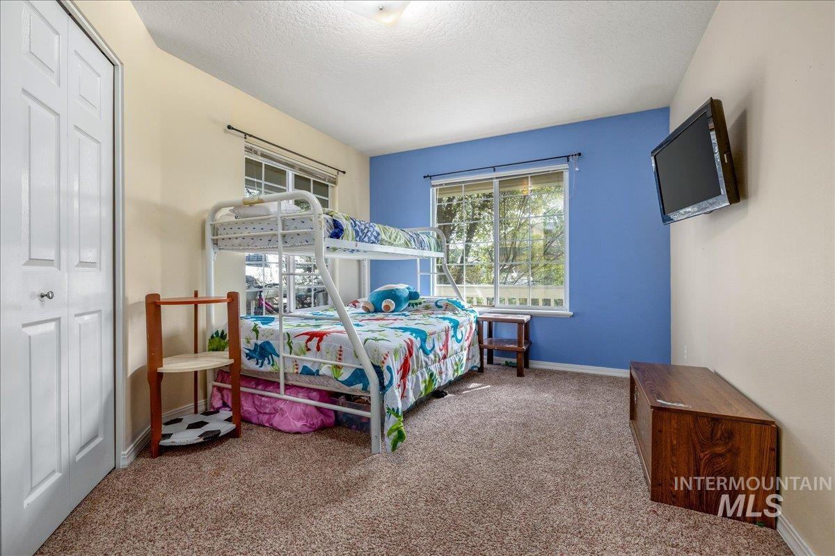Bedroom featuring light colored carpet, a closet, and a textured ceiling