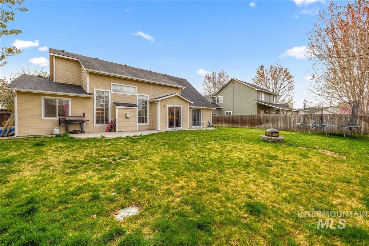 Back of property featuring a trampoline, a fenced backyard, a fire pit, and a patio area
